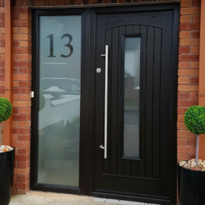 Sleek black minimalist front door with a slim vertical glass panel, designed for a modern, understated aesthetic